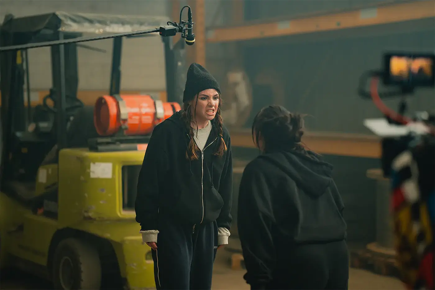 Junge Frau im Kapuzenpullover spielt eine intensive Szene in einer Lagerhalle, Standbild aus dem IAF Abschlussfilm Mülltonne 2025