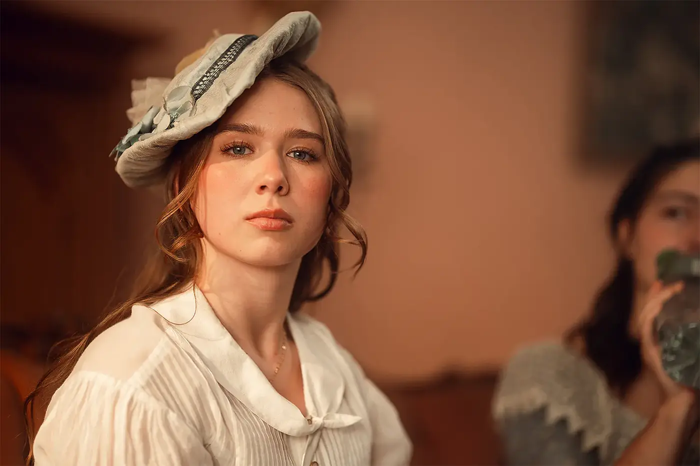 Junge Schauspielerin in weißem Kostümkleid mit Hut, Standbild aus dem IAF Abschlussfilm 19. Jahrhundert 2025