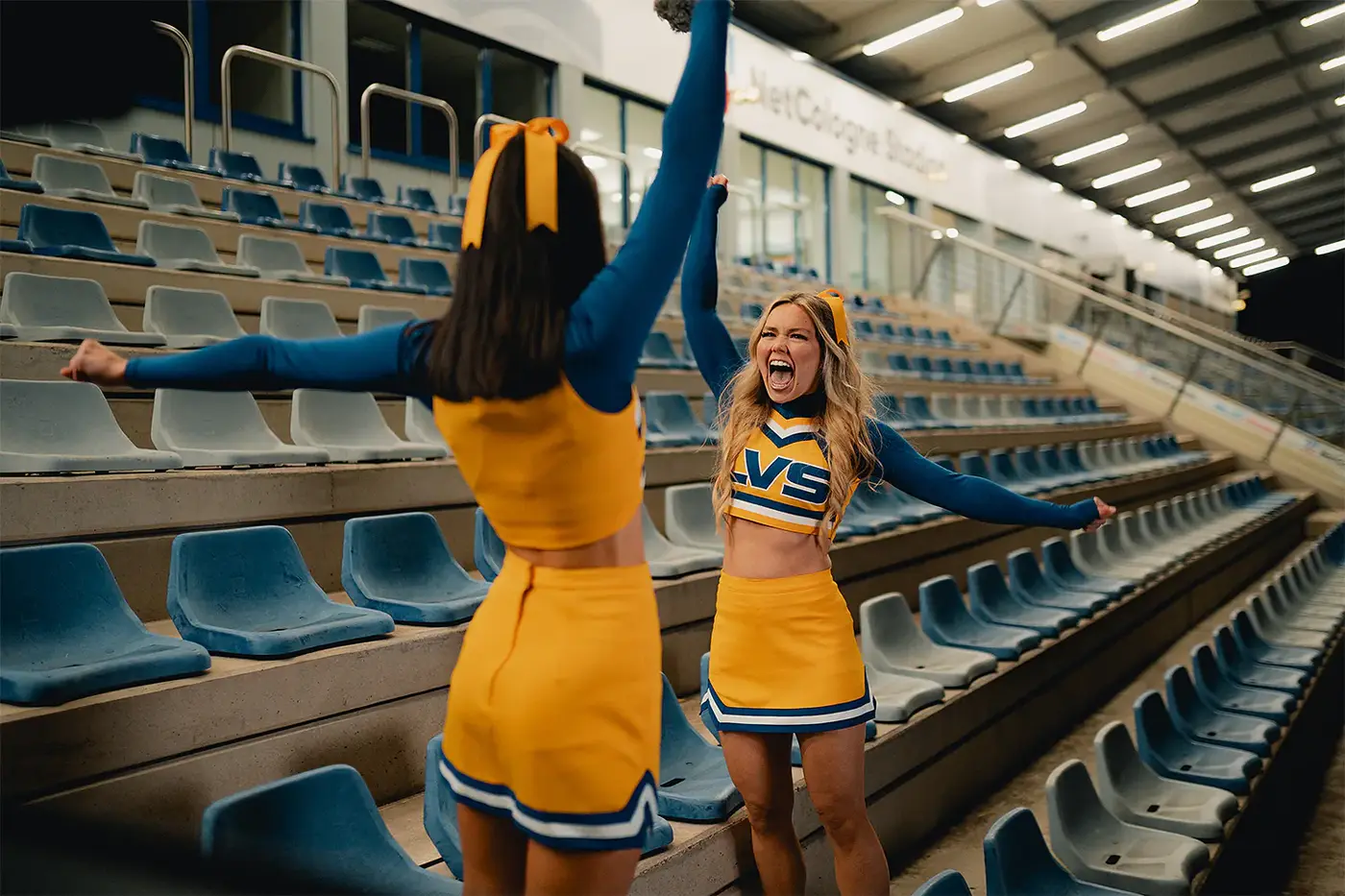 Zwei Cheerleaderinnen jubeln ausgelassen auf einer Stadiontreppe, Standbild aus dem IAF Abschlussfilm Cheerleader 2025